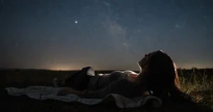 Person som tittar upp mot stjärnhimlen under meteorregnet Lyriderna