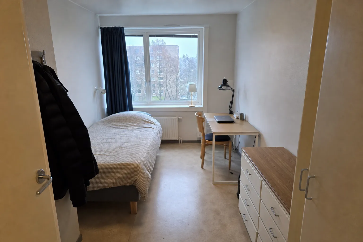 Enkelt inrett studentrum med säng, skrivbord och fönster, typiskt för semesterbostäder Sverige.