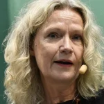 Person i mörkt rum med ansikte upplyst av mobilskärm, spänd och uppslukad