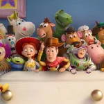 Toy Story-karaktärer samlade på en vit låda framför blå vägg. Woody, Buzz Lightyear, Mr Potato Head, Rex, Hamm och andra klassiska leksaker från filmserien pose